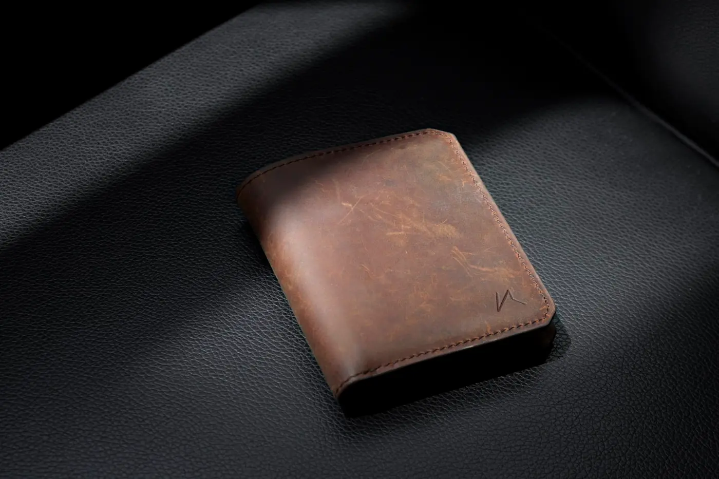 A premium brown leather wallet on a dark surface